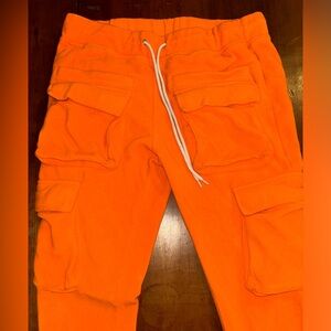 Orange joggers that zip at the end and have elastic waistband